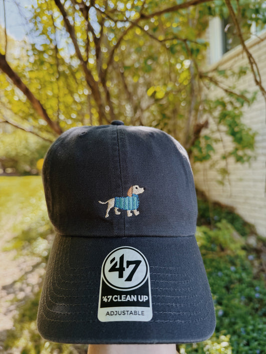Navy blue cap with a dog illustration and '47' branding against a blurred outdoor background